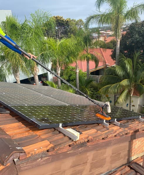 Technician cleaning solar panels on a rooftop