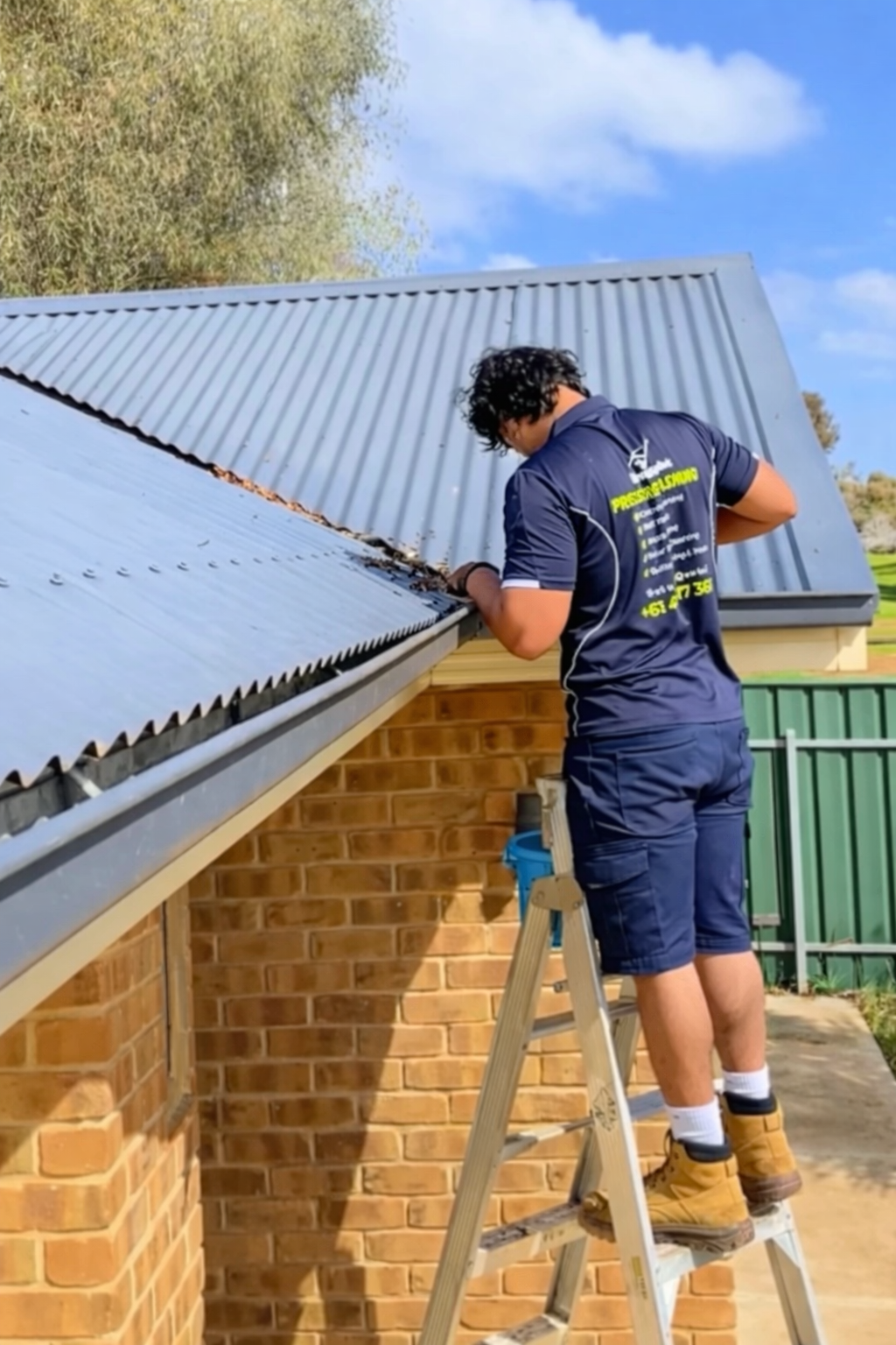 Gutter cleaning technician on a ladder cleaning gutters